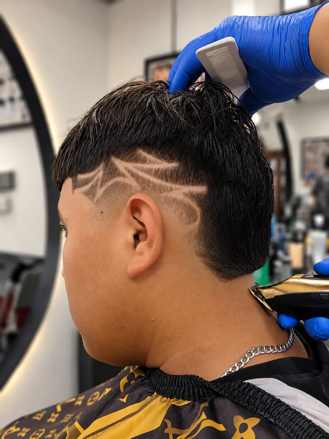 Barber lining up a design with clippers on the back of a client’s head